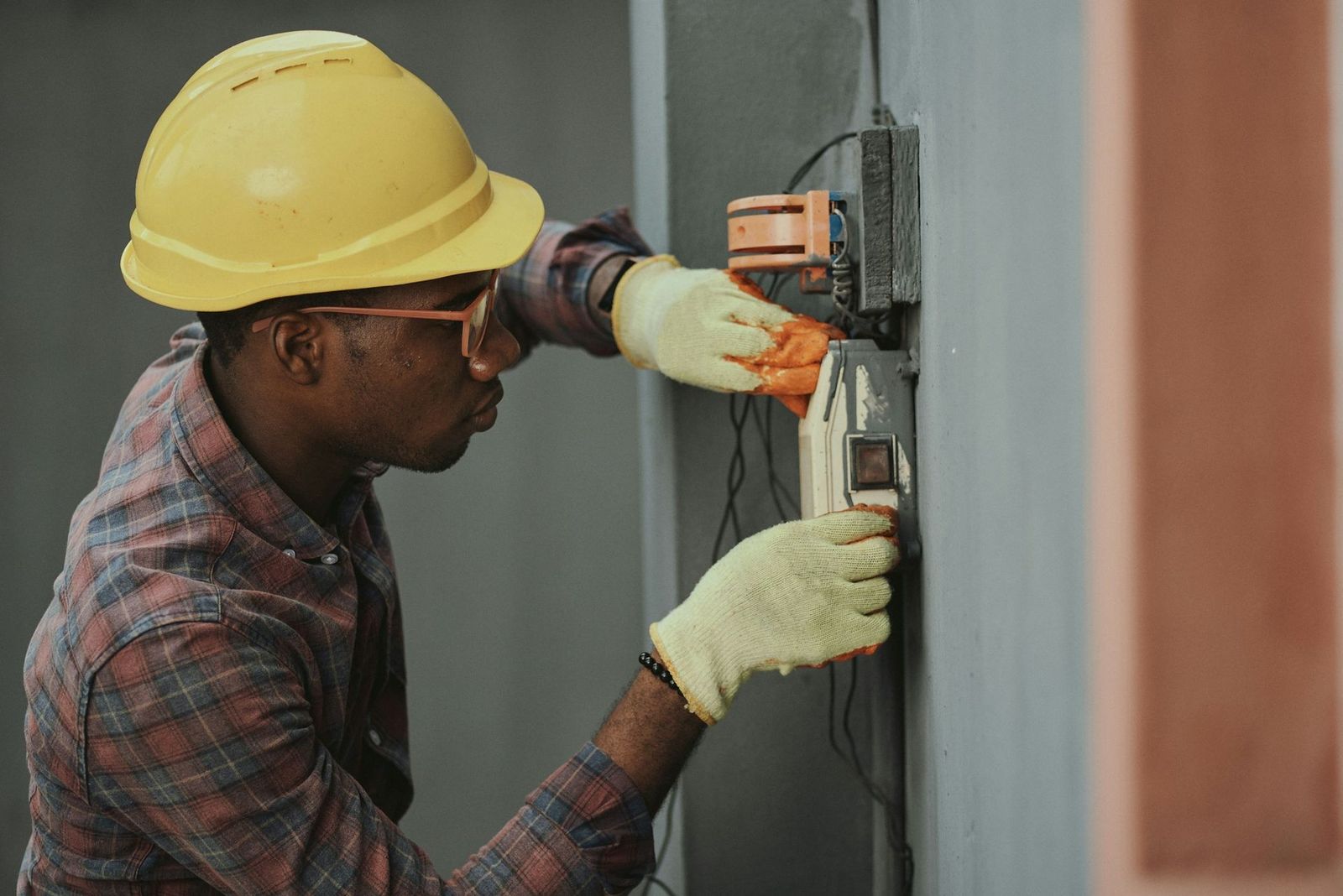 Electrician in a hard hat working inside an electrical enclosure