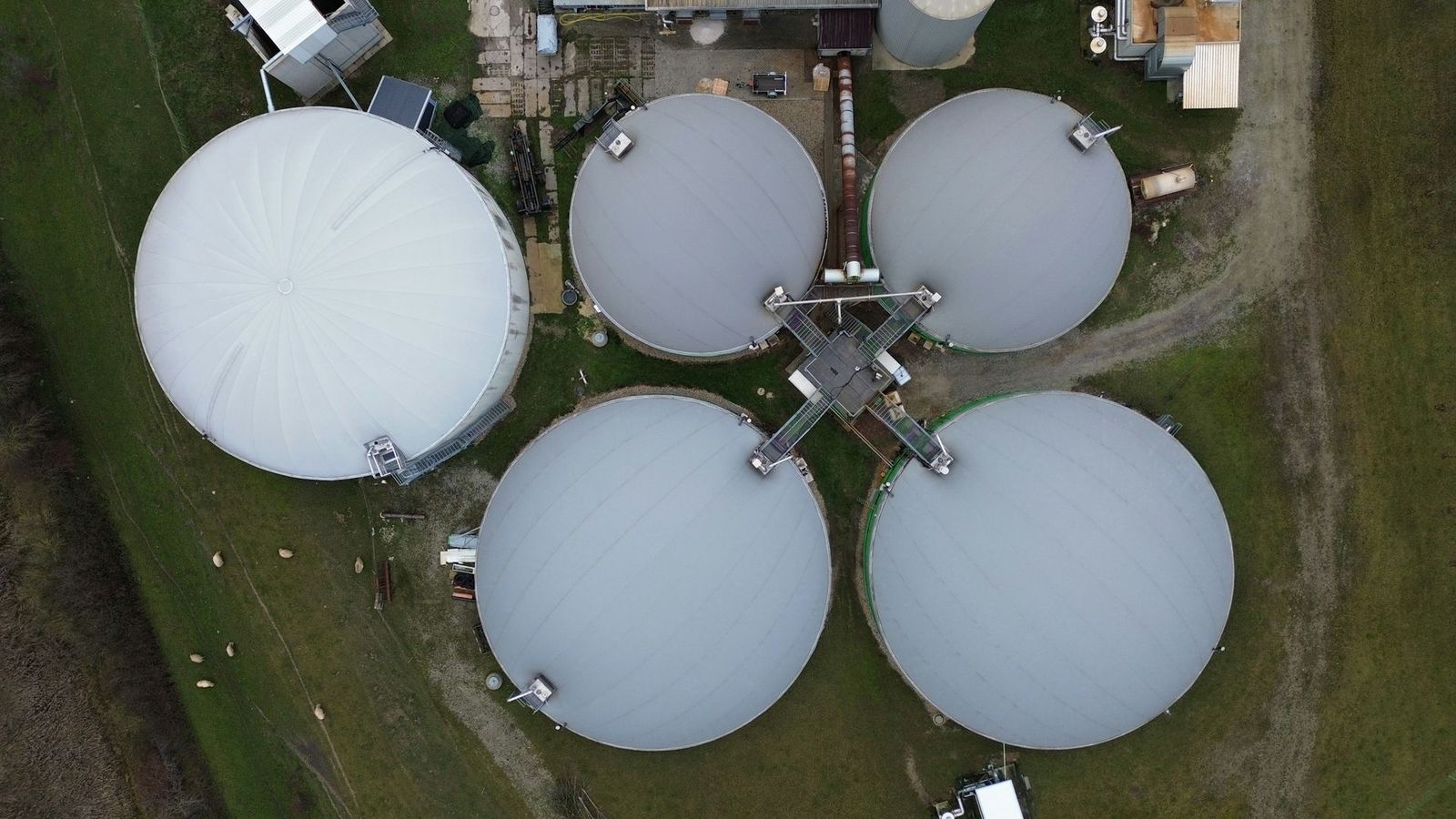 Aerial view of anaerobic digester tanks in a green field