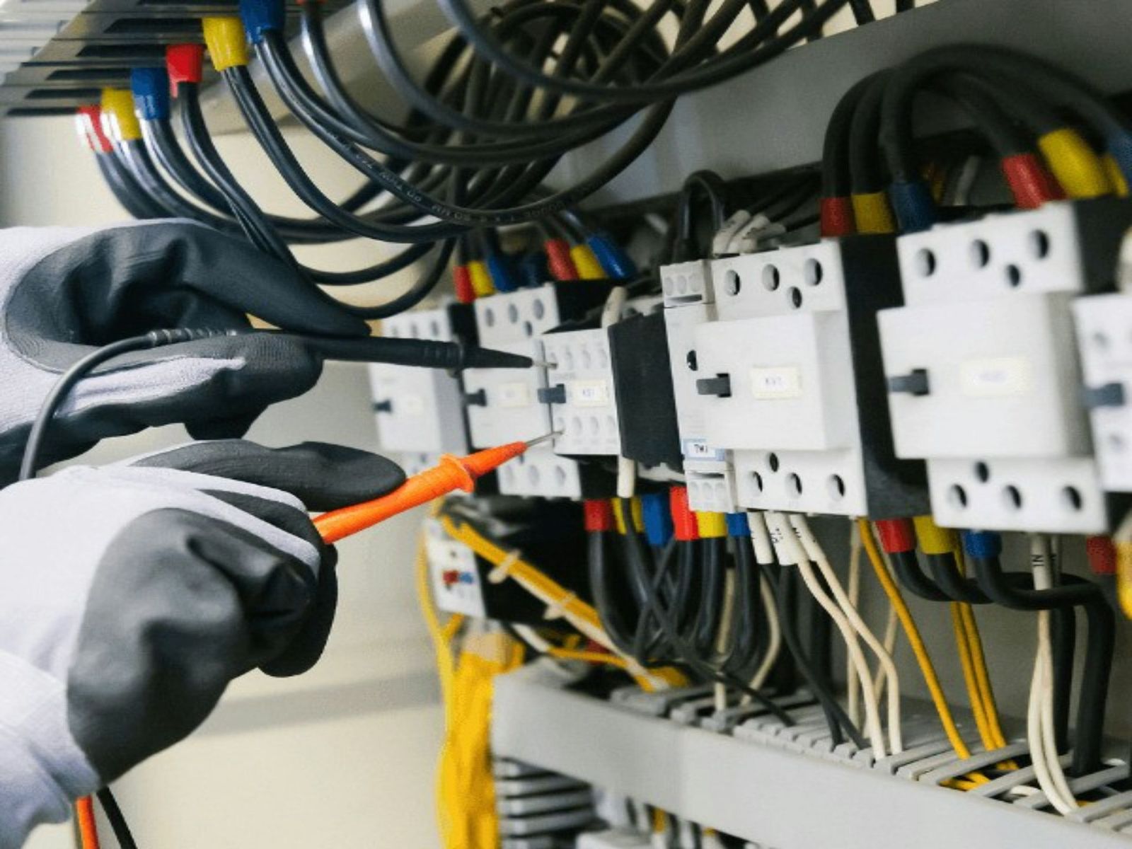Electrician testing terminal connections inside a control cabinet